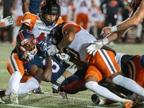 Montreal Alouettes wide receiver Eugene Lewis (87) is brought down by B.C. Lions' Sione Teuhema (top) and Lions' Loucheiz Purifoy during first half CFL football action in Montreal on Friday, September 9, 2022.