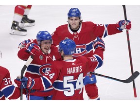 Montreal Canadiens' Brendan Gallagher, left, and Chris Wideman, top, congratulate teammate Jordan Harris after scoring against Florida Panthers during first period in Montreal on April 29, 2022.