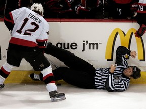 Linesman Pierre Racicot falls to the ice as Ottawa Senators Mike Fisher tries to dig the puck out from under him during second period of pre-season hockey against the Montreal Canadiens September 30, 2006.
