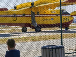A young boy covers his ears as he watches one of two Super Scooper firefighting aircrafts arrive from Quebec, at the Van Nuys airport in Los Angeles in August 2016.