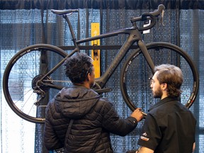 Philip Guimond (right) displays an electric bicycle at the Montreal International Auto Show in 2020.