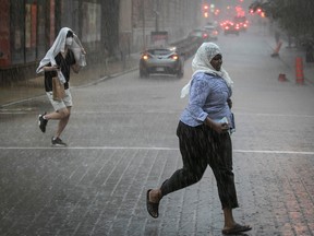 People rush for cover  in downtown Montreal during a rainstorm in June 2022.