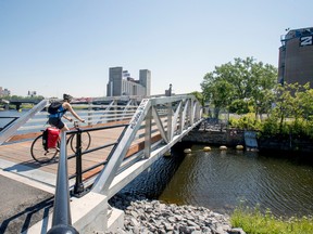A cyclist crosses a footbridge over the divide between the Peel Basin, left, and the Wellington basin in the Bridge-Bonaventure district south of downtown Montreal Thursday June 27, 2019. The proposed Bridge-Bonaventure real estate mega-project is essentially Griffintown 2.0, Steven High says.