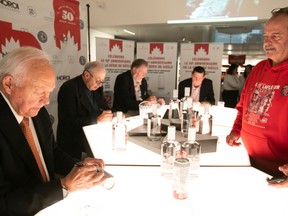 Louis Theberge gets autographs from team members of the 1972 Summit Series, including Yvan Cournoyer, far left, Guy Lapointe, Peter Mahovlich and Serge Savard, during a promo event at a downtown SAQ on Thursday Oct. 6, 2022.