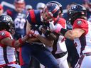 Alouettes received Jake Wieneke is tackled by Redblacks' Patrick Levels, left, and Adam Auclair during first-half action at Molson Stadium on Monday.