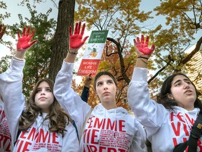 Young women with their hands painted red participate in a march through the streets of Montreal to show solidarity with Iranian women on Saturday, Oct. 22, 2022.