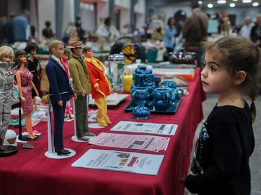 Six-year-old Alice Picardat looks at dolls at a vintage bazaar at Saint-Jean-Berchmans Church in Montreal on Sunday, Oct. 23, 2022.