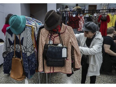 Monique Léandre looks at a rack of clothing at a vintage bazaar at Saint-Jean-Berchmans Church in Montreal on Sunday, Oct. 23, 2022.