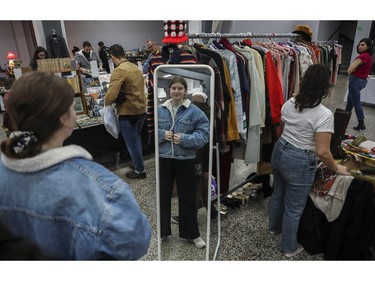 Laurelie Perrault checks out an old jean jacket at a vintage bazaar at Saint-Jean-Berchmans Church in Montreal on Sunday, Oct. 23, 2022.