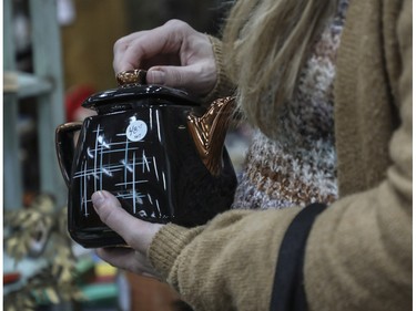 A woman looks at a tea pot at a vintage bazaar at Saint-Jean-Berchmans Church in Montreal on Sunday, Oct. 23, 2022.