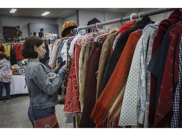 Léa Massouty looks through a rack of clothing at a vintage bazaar at Saint-Jean-Berchmans Church in Montreal on Sunday, Oct. 23, 2022.