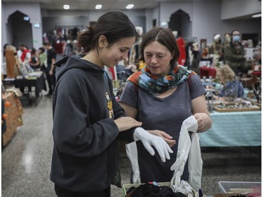 Lou Gabriac (left) and her mother ,Morgan Guitton, look at gloves at a vintage bazaar at Saint-Jean-Berchmans Church in Montreal on Sunday, Oct. 23, 2022.