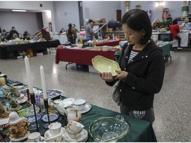 Lisa Wei, an art collector, looks at an item at a vintage bazaar at Saint-Jean-Berchmans Church in Montreal on Sunday, Oct. 23, 2022.
