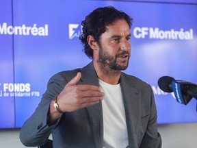Olivier Renard gestures while speaking into a microphone in a conference room