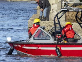 Steven Evans looks in the water near his home on the shore of Milles-Îles River Oct. 29, 2022, as Laval firefighters search the water for a missing infant.
