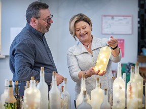Marie Gallagher shows one of her illuminated bottles to Michel Trottier at the Artisans Baie-D'Urfé Curling Club Craft Fair on Saturday.