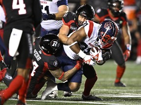 Alouettes running back William Stanback (31) is tackled by Ottawa Redblacks linebacker Adam Auclair (32) and defensive back Damon Webb (34) during second half CFL football action in Ottawa on Friday, Oct. 14, 2022.