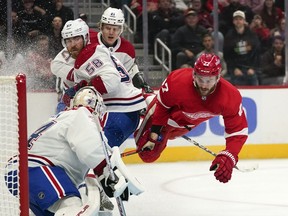 Detroit Red Wings centre Michael Rasmussen (27) is tripped up by Canadiens defenceman David Savard (58) in front of the net as goaltender Jake Allen defends on Friday, Oct. 14, 2022, in Detroit.