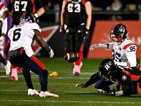 Montreal Alouettes defensive-end Thomas Costigan forces a fumble by Ottawa Redblacks quarterback Nick Arbuckle, leading to a touchdown by Als strong-side linebacker Adarius Picket, left, during first half in Ottawa on Oct. 14, 2022.