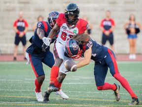 Montreal Alouettes’ Marc-Antoine Dequoy, right, and Davis Alexander tackle Ottawa Redblacks’ Llevi Noel during first half in Montreal on June, 3, 2022.