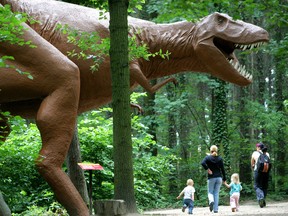 Visitors casually walk past a Tyrannosaurus rex at Dinosaur Park in Germany.