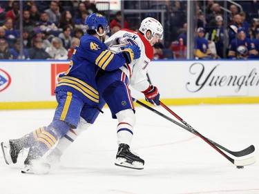 Montreal Canadiens centre Kirby Dach (77) controls the puck as he gets checked by Buffalo Sabres defenceman Casey Fitzgerald (45) during the third period at KeyBank Center in Buffalo, N.Y., on Oct. 27, 2022.