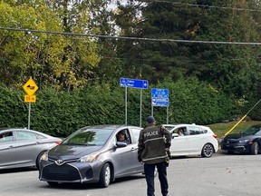 A Sûreté du Québec officer redirects traffic at a roadblock shortly after a shooting in Estérel on Friday, Oct. 7, 2022.