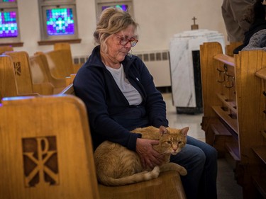 Anne Mackay holds Oscar, a cat that was a stray that she rescued from a Montreal winter about 5 years ago, at a Blessing of the Animals event at the church in Notre-Dame-de-Grâce area on Sunday, Oct. 2, 2022.