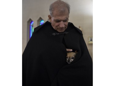 Sainte-Catherine-de-Sienne parish priest Jean-Pierre Couturier strokes his dog Palou dog at a Blessing of the Animals event at the church in Notre-Dame-de-Grâce on Sunday, Oct. 2, 2022.