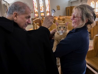 Sainte-Catherine-de-Sienne parish priest Jean-Pierre Couturier blesses Oscar, a cat that was a stray rescued from a Montreal winter about 5 years ago by Anne Mackay, at a Blessing of the Animals event at the church in Notre-Dame-de-Grâce on Sunday, Oct. 2, 2022.