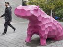 A man walks by a pink Hippo at the site of the former Jardin Guilbault in Montreal, Friday, Oct. 7, 2022. The site once housed a zoological park, created by Joseph-Edouard Guilbault in the 1800s.