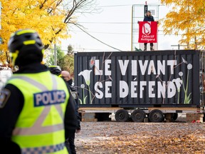An activist is chained to a shipping container blocking the entrance to the Valero oil transfer terminal in the Port of Montreal in Montreal on Wednesday, October 19, 2022. Protestors demand the closure of the 9B oil pipeline, owned by Enbridge, which ends at this terminal.
