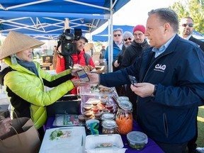 El líder de la Coalición Avenir Québec, François Legault, paga a un vendedor por comida durante una parada de la campaña electoral en un mercado en Magog, el domingo 2 de octubre de 2022.