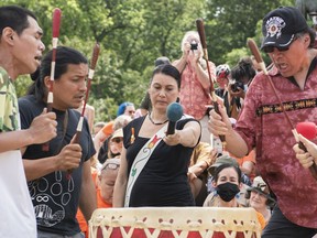 Nakuset, centre, executive director of the Native Women's Shelter of Montreal, holds a microphone for drummers during a gathering in Montreal, Thursday, July 1, 2021. The Indigenous advocate says a Montreal child and family services agency isn't serious about improving care for Indigenous youth and that the watchdog agency overseeing it lacks teeth.