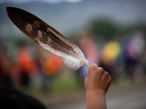 A woman holds an eagle feather. "Self-identification, a mechanism by which institutions purport to help Indigenous people, has become yet another source of harm for us and our communities," Brandon Montour writes.
