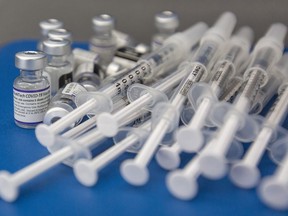 Syringes and vials of Pfizer-BioNTech COVID-19 vaccine are seen on a work surface in Kingston, Ont., Saturday, Dec. 18, 2021. Health Canada says Canadians can now be given the Pfizer-BioNTech COVID-19 booster vaccine that targets the BA.4 and BA.5 strains of the Omicron variant.