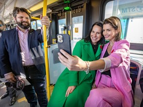 Montreal Mayor Valérie Plante and Quebec Transport Minister Geneviève Guilbault, right, take a selfie during the inauguration of the SRB Pie-IX bus rapid transit project on Thursday November 3, 2022, as STM board chair Éric Alan Caldwell looks on.
