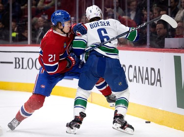 Canadiens defenceman Kaiden Guhle (21) grimaces as he drives Vancouver Canucks right wing Brock Boeser (6) in to the boards during NHL action in Montreal on Wednesday, Nov. 9, 2022.