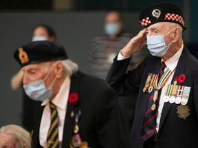 Veteran Bruce Udle salutes during the National Anthem with William Talbot at a commemorative ceremony at Ste-Anne's Hospital on Monday.