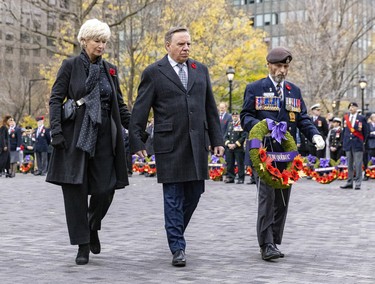 Quebec Premier François Legault and wife, Isabelle Brais, are accompanied by Thomas Irvine, president of the Quebec Command of the Royal Canadian Legion, as they walk to the cenotaph to lay a wreath during Remembrance Day ceremony in Montreal on Friday, Nov. 11, 2022.