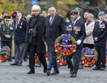 Quebec Premier François Legault and wife, Isabelle Brais, are accompanied by Thomas Irvine, president of the Quebec Command of the Royal Canadian Legion, as they walk to the cenotaph to lay a wreath during Remembrance Day ceremony in Montreal on Friday, Nov. 11, 2022.