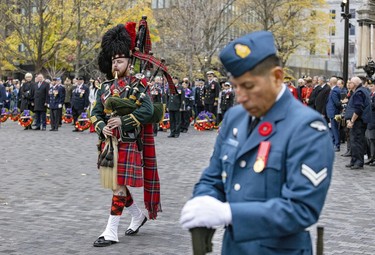 A Black Watch piper plays the Lament as he walks past Corporal Richard Condor standing sentry at the cenotaph during Remembrance Day ceremony in Montreal on Friday, Nov. 11, 2022.