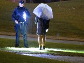 A Laval police officer stops a woman walking on school grounds after a shooting in a park located next to Collège Montmorency in Laval on Friday, Nov. 11, 2022.