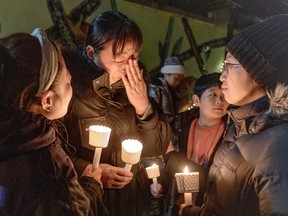 Sujing Nie, mother of missing teenager Feng Tian cries while receiving support from Jin Zhou, left, and Li Xia at a candlelight vigil to call attention to the boy's disappearance on Nov. 14, 2022.
