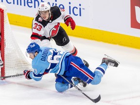 Canadiens' Evgenii Dadonov trips over New Jersey Devils' Ryan Graves's stick during the second period of a National Hockey League game in Montreal Tuesday Nov. 15, 2022.