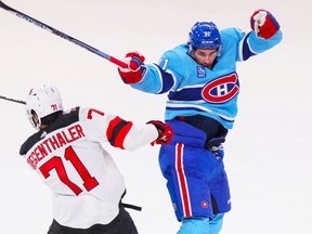 Canadiens' Sean Monahan bounces off a check by New Jersey Devils' Jonas Siegenthaler during the first period of a National Hockey League game in Montreal Tuesday Nov. 15, 2022. The Canadiens were wearing their Reverse Retro jerseys for the game.