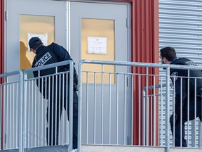 Police look in a doorway outside the Collége Lionel-Groulx in Ste-Thérèse, north of Montreal, on Friday, November 18, 2022, following reports of a suspicious individual outside CEGEP.