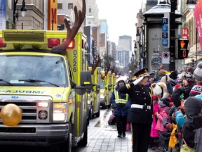 An Urgences Santé officer salutes the crowd as she follows reindeer equipped ambulances during the Santa Claus parade in Montreal on Saturday, Nov. 19, 2022.