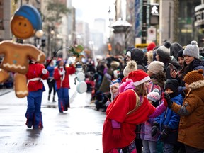 One of Santa's elves greets children waiting to see Santa during the Santa Claus parade in Montreal on Saturday, Nov. 19, 2022.