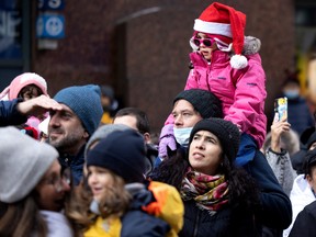 A young girl enjoys privileged seating above the crowd as they wait for the arrival of Santa during the Santa Claus parade in Montreal on Saturday, Nov. 19, 2022.